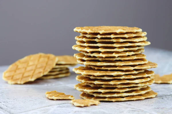 Fotokopi alanı olan gri bir zemin üzerinde bir yığın tereyağlı waffle kurabiyesi, seçici odaklanma. Waffle cipsleri yakın plan. Lezzetli ev yapımı ince waffle.