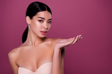 Göğüs dekoltesi giyen rüya kadının portresi pembe renkli fotokopi masasında vücut bakımını gösteriyor..