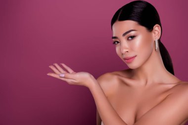 Göz kamaştırıcı kadının portresi pembe arkaplan üzerinde izole edilmiş boş alan üzerinde kozmetik ürünü gösteriyor.