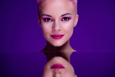 Ayna yüzeyi olan sıra dışı bir stüdyo fotoğrafı. Moda mankeni, makyaj salonu tanıtımı, mor arka plan..