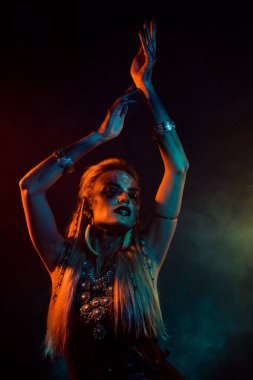 Çılgın, havalı, gizemli kadının dikey fotoğrafı gotik Valkyrie kostümü giyip izole karanlık sis arka planında dans ediyor..