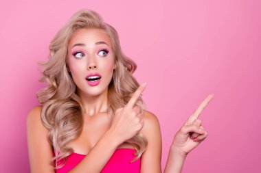 Heyecanlı, oyuncak bebek stili güzel bir bayanın fotoğrafı. Parmakla göstererek pembe arka planda reklam sunuyor..