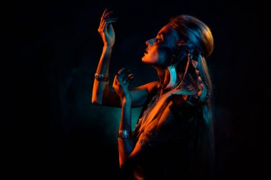 Dua eden hayalperest kadının fotoğrafı gotik Valkyrie kostümü giyer Trance portakal rengi arka plan.