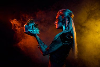 Vahşi mistik kadının fotoğrafı gotik Valkyrie kostümü giyip el ele tutuşurken izole edilmiş turuncu sis arkaplanı..