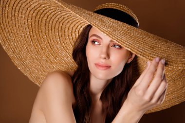 Kadın turist dokunuşlu güneş şapkası. Pastel arka plandaki spa merkezinde bronzlaşma prosedürünü bekle..