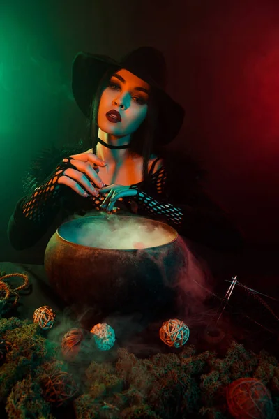 强大的巫婆用大锅药水进行魔法仪式的照片召唤恶魔爬上霓虹灯的背景 — 图库照片