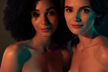 Kendinden emin, lüks kadınların çıplak omuzlarını kucaklayan, gülümseyen, izole edilmiş koyu renk arka plan fotoğrafı..