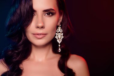 Çekici, baştan çıkarıcı, çıplak bir kadının fotoğrafı. Küpe takıyor. Boş, izole, siyah bir arka plan..