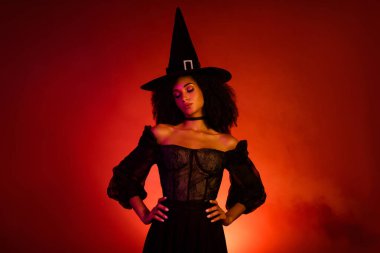Büyüleyici ortaçağ kadın cadısının fotoğrafı Cadılar Bayramı için kırmızı arka planda belirdi..