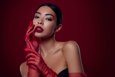 Güzel Asyalı kızın fotoğrafı, baştan çıkarıcı, baştan çıkarıcı, dokunaklı dudaklar, izole, koyu kırmızı arka planda omuzlar..