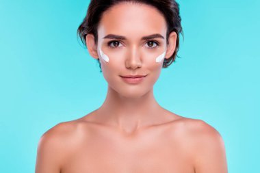 Yanaklarında krema olan kadının fotoğrafı. Kamera aynasına bak. Mavi arka planda her gün sabah hijyeni var..