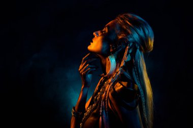 Hayalperest bir kadının fotoğrafı gotik valkyrie giyer ve izole edilmiş koyu turuncu arkaplan ayini yapar..