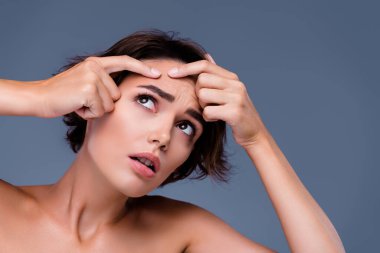 Her gün sabah hijyen temizliği yapan üzgün kadının fotoğrafı. Aynaya bak. Gri arkaplandaki sivilce kavramına dokun..