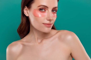 Güzel bir genç kızın fotoğraf portresi yüz göz bantları promosyon spa salonu kapalı Cyan renk arka plan.