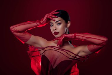 Güzel Asyalı kızın fotoğrafı baştan çıkarıcı model yüksek moda omuzları izole edilmiş koyu kırmızı arka plan..