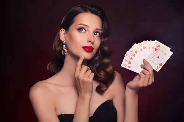 Photo of chic classy lady poker player hold cards touch face thinking about lucky strategy win over dark background.