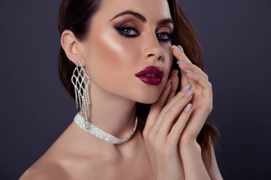 Gri arka planda izole edilmiş lüks geçmişe dönük mücevheri olan kadın butik mağazası için poz veren sevimli kadının portresi..