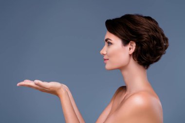 Kadın güzellik tanıtımcısının fotoğrafı. İpeksi yumuşak vücut için gri arka planda yeni bir ürün gösteriyor..