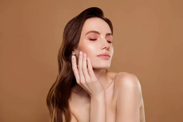 Dokunmatik yeni yüz kremi kullanan nazik, çarpıcı kadının fotoğrafı. Pastel renkli arka planda güzellik ürünü reklamı..