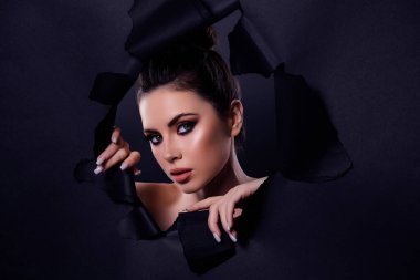 Güzel, genç bir modelin portresi göz kamaştırıcı bir kadın içinde koyu renk arka planda ideal bir yüzle poz veriyor..