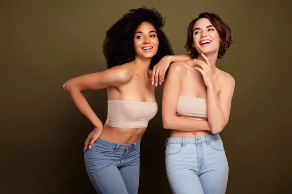 Portrait of two flawless friends women laughing together on self acceptance therapy isolated on khaki color background.