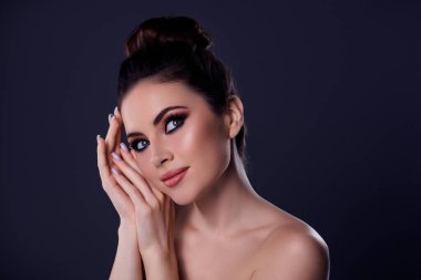 Hayalperest bir kadının, koyu renk arka planda izole bir moda partisinde çekici makyajla yüzüne dokunduğu fotoğraf..