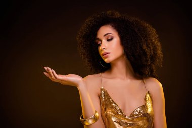 Harika bir kadının portresi boş bir alanda duruyor kahverengi arka planda izole edilmiş altın renkli şık kıyafetler giyiyor..