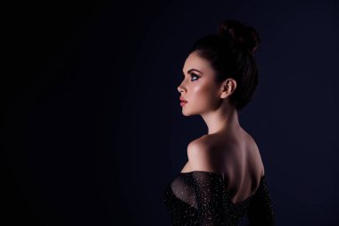 Lüks model çarpıcı kızın yan fotoğrafı. Kopyalama alanı gibi görünüyor. Zaman zaman koyu renk arka planda kendini güvende hisset..