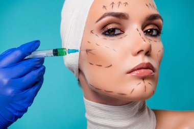 Plastik cerrahi hastası bayanın yanaklarına botoks enjekte edilirken çekilmiş fotoğrafı..