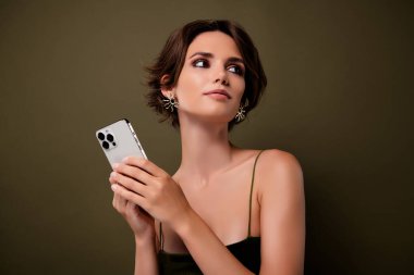 Photo of gorgeous lady hold smart phone device look on green empty space background.