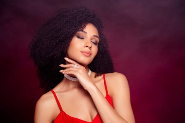 Photo of dreamy classy model presenting jewellerry ring with diamonds studio photo on red marsala background.