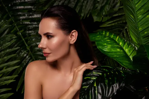Side profile shot of charming seductive woman brunette hair hiding in rainforest jungle leaves healthy pampering.