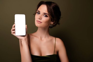Şık, çekici, zengin bir kadının fotoğrafı. Yeşil arkaplan üzerinde beyaz ekran boş alanı olan akıllı telefon cihazını tut..