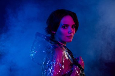 Çekici, havalı bir kızın fotoğrafı. Kameraya bak. Yağmurlu, koruyucu giysiler giy..