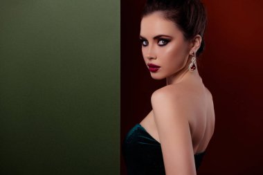 Pırlanta küpeli muhteşem bir kadının portresi. Kırmızı arka planda izole edilmiş mücevher afişini destekliyor..