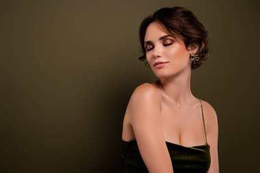 Kapalı dumanlı gözlü klas kız arkadaşın fotoğrafı yeşil boş arkaplanda duruyor ve moda elbisesi giyiyor..