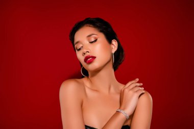 Koreli genç bayanın fotoğrafı boş görünüyor. Omzuna dokun. Kırmızı arka planda izole edilmiş siyah deri kıyafetler giy..