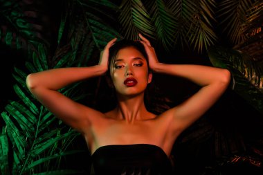 Vietnamlı Koreli kızın fotoğrafı. Koyu renk ağaçların üzerindeki saçlara dokunuyor..