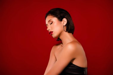 Muhteşem Koreli genç bayan seksi manken fotoğrafı kırmızı arka planda siyah deri elbise giyer..