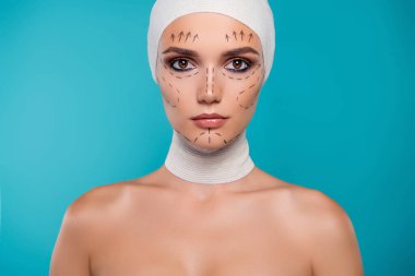 Tıbbi bandajlı plastik cerrahi hastası kadının portresinin arka planında düzeltme işaretleri var..