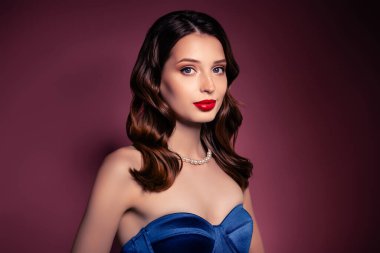 Esmer, kıvırcık saçlı kızın fotoğrafı kahverengi arka planda pahalı bir gece elbisesi giyiyor..