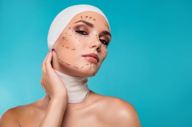 Cyan parlak renk arkaplan üzerinde estetik ameliyat için çizgili kadın dokunmatik yüz fotoğrafı.