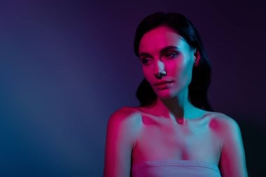 Kadın fotoğrafı. Pembe neon ışığın altındaki boş alana bak. Ayrı, koyu renk arkaplan..