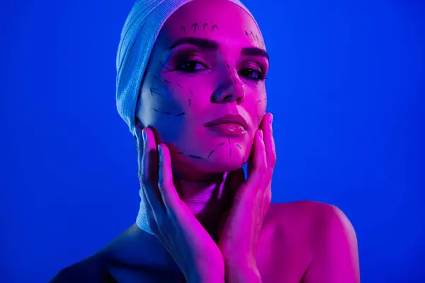 青いネオンバックグラウンド上のプラスチック手術図面で魅力的なティエントな女性のタッチ指の顔の写真 — ストック写真