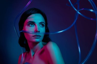 Kadın fotoğrafı, koyu morötesi neon arkaplanda izole edilmiş plastik kablolara bakın..