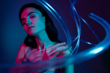 Gözleri kapalı bir kadının fotoğrafı parmaklarını birbirine değdirerek plastik güzellik kablolarının etrafını sarar ve ultraviyole arka plan izole eder..