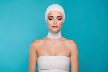 Bandajlı kadın hastanın fotoğrafı gözleri kapatıyor yüz noktalı izler, estetik ameliyat için hazırlanmış..