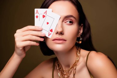 Göz kamaştırıcı bayan riskli poker oyuncusunun fotoğrafı. Kahverengi arkaplanda iki kart, kraliyet flaşı var..