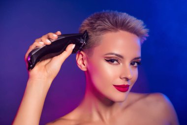 Sis neon ultraviyole arkaplan üzerine profesyonel elektrikli makasla saç kesen bir kızın yakın plan fotoğrafı..