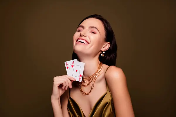 カードを保持する陽気でエレガントな女性の写真は 茶色の背景に隔離されたフルハウスと勝利ゲームを演じます — ストック写真